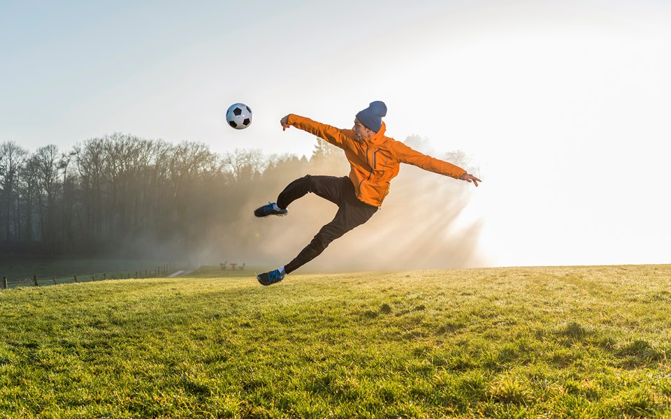 Fotbollsspelare som hoppar högt med boll